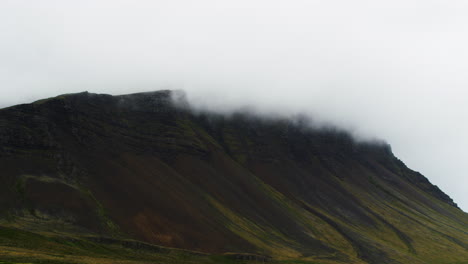 White-clouds-rolling-over-mountain-peak-in-Iceland,-zoom-in-view
