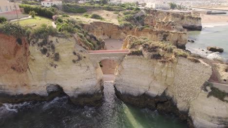 Aerial-pullback-over-Arch-bridge-at-Praia-dos-Estudantes-in-Lagos,-Algarve