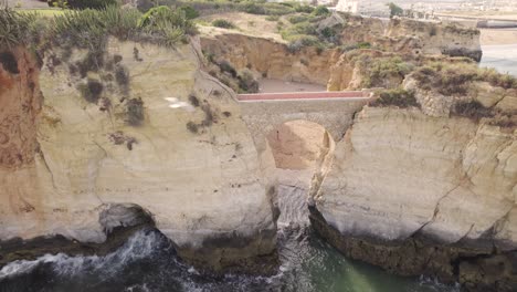 Aerial-shot-of-Ponta-da-Piedade-coastal-cliff-path-and-bridge-in-Portugal