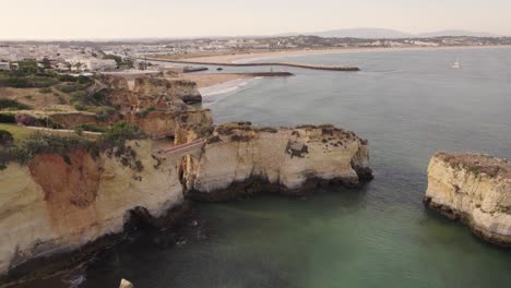 Steinbogenbrücke-Am-Praia-Dos-Estudantes-Gegen-Das-Stadtbild-Von-Lagos,-Algarve