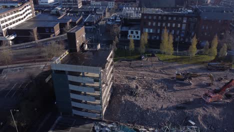 Demolished-multi-storey-car-park-concrete-construction-debris-in-town-regeneration-aerial-right-orbit-view