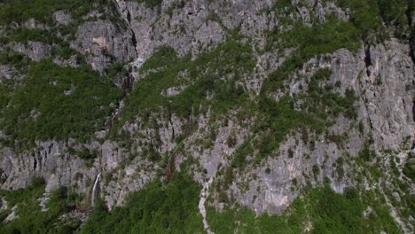 Rocky-slope-of-gigantic-mountain-with-meadows-and-forests-on-the-top-of-Alps-in-Theth,-Albania