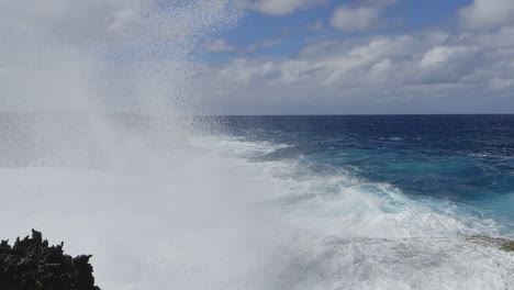 Large-waves-crashing-against-rocky-Pacific-island-cliffs,-powerful-ocean-swell