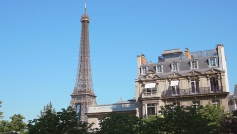 Torre-Eiffel-Con-Edificio-Arquitectónico-Estilo-Haussmann-Y-Cielo-Azul-En-París,-Francia---4k