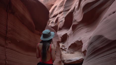 Back-of-young-woman-with-photo-camera-walking-in-a-narrow-slot-sandstone-canyon,-amazing-landscape-and-natural-beauty-of-Antelope-Canyon,-Arizona-USA,-slow-motion