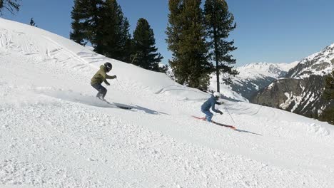 Male-and-Female-pro-skier-showing-nice-downhill-ski-turns-in-wonderful-snowy-mountain-landscape-in-the-alps