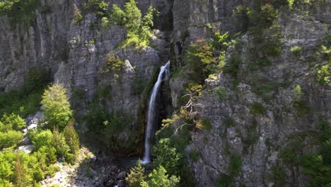 Beautiful-waterfall-on-rocky-slope-of-Alps-Albanian-mountain,-snowy-water-splashing-on-cliffs