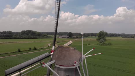 Luftnahaufnahme-Von-Dochten-Und-Bau-Einer-Typischen-Holländischen-Windmühle,-Die-Sich-Dreht-Und-Die-Breitere-Agrarlandschaft-Der-Niederlande-Enthüllt