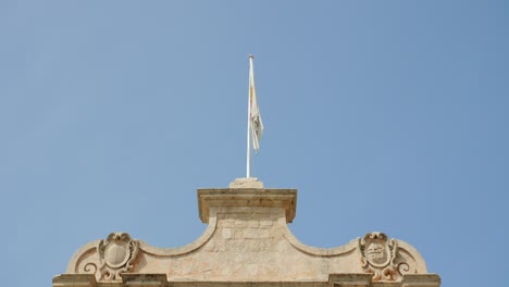 Bandera-De-Mdina-Ondeando-En-La-Parte-Superior-De-La-Puerta-De-La-Ciudad-En-Malta-Contra-El-Cielo-Azul-Claro