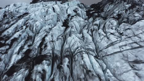 Jagged-ice-flowing-down-mountain-as-Glacier,-Sólheimajökull,-aerial