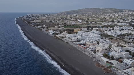 Drone-shot-of-Perissa,-Santorini,-Greece,-during-off-season,-4K