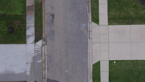 Overhead-view-of-street-and-sidewalk-and-driveway-with-a-car-driving-through