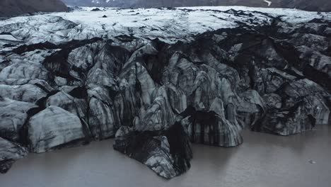 Edge-of-retreating-glacier-in-Iceland-covered-with-black-sand,-global-warming