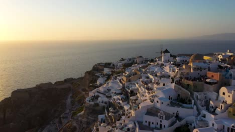 Smooth-panning-shot-over-Oia-built-on-a-cliff-during-sunset,-Santorini-island,-Cyclades,-Greece