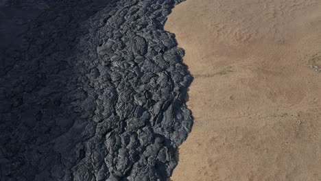 Edge-of-black-basalt-field-solidified-lava-dark-rock,-aa-flow,-Iceland