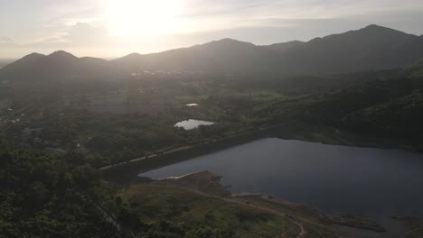4K-Luftaufnahmen-Fliegen-Hoch-Mit-Sonnenlicht-über-Berge-Im-Hintergrund-In-Der-Nähe-Des-Khlong-Bod-Reservoirs-In-Nakhon-Nayok,-Thailand