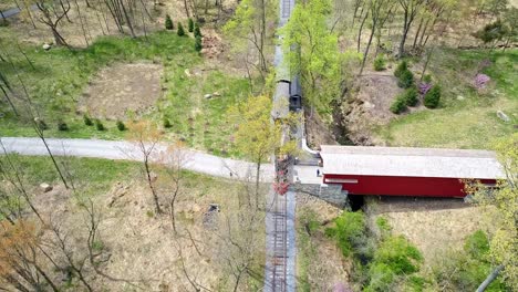 An-Aerial-View-of-an-1860's-Steam-Passenger-Train-Traveling-Thru-a-Wooded-Area-as-it-Passes-a-Covered-Bridge-on-a-Lonely-Single-Rail-Road-Track