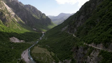 Valley-of-Thethi-in-Albania,-river-streaming-through-high-Alps-mountains-covered-in-green-lush-vegetation