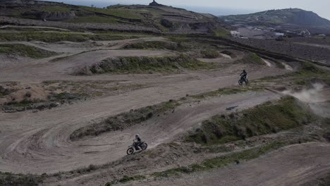 Aerial-shot-panning-left-as-riders-on-motocross-track-hit-a-jump