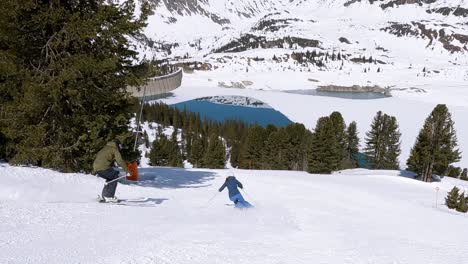 Two-young-skiers-showing-short-ski-turns-in-a-ski-resort-with-beautiful-mountain-lake-view-in-Tyrol