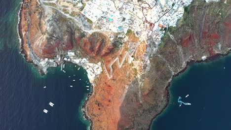 Vuelo-Sobre-El-Hermoso-Pueblo-De-Oia-Construido-Sobre-Un-Acantilado-Durante-La-Puesta-De-Sol,-Isla-De-Santorini,-Cícladas,-Grecia