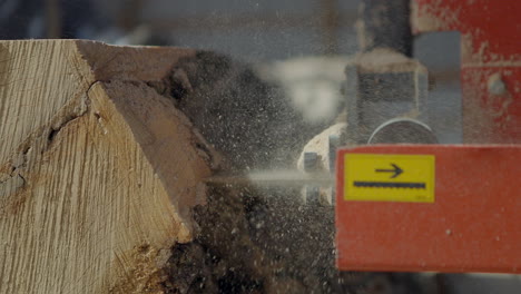 Large-industrial-saw-blade-finishing-a-cut-through-a-large-tree-trunk-in-slow-motion-closeup