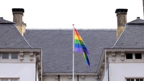 Rainbow-colors-of-LGBTQ+-flag-on-top-of-historic-city-hall-in-Zutphen,-The-Netherlands,-waving-gently-from-the-Dutch-historic-facade-in-support-of-community