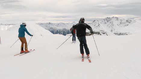 Cinematic-show-skiing-with-3-ski-athletes-in-a-ski-resort-high-up-in-the-mountains-with-amazing-panorama-view-over-the-snowy-mountain-tops