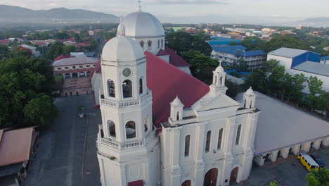 A-glowing-shiny-majestic-landscape-rotating-drone-view-over-a-Basilica-Church-of-the-city-having-river-and-mountains,-Batangas,-Philippines