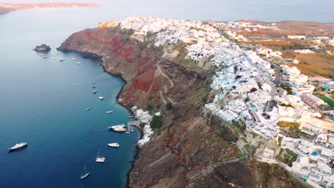 Aerial-video-of-famous-white-,colourful-picturesque-village-of-Oia-built-on-a-cliff-during-sunset,-Santorini-island,-Cyclades,-Greece