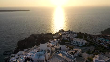 Smooth-panning-shot-over-windmill-in-Oia-built-on-a-cliff-during-sunset,-Santorini-island,-Cyclades,-Greece