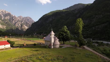 Peaceful-alpine-village-of-Theth-in-Albania,-traditional-church-and-houses-with-mountains-background