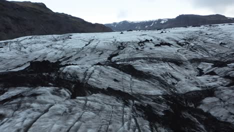 Dark-frozen-ice-at-bottom-of-Sólheimajökull-glacier-in-Iceland,-aerial