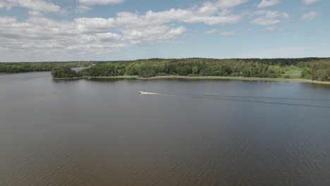 Drone-approaching-far-away-motor-boat,-in-a-Scandinavian-lake,-Sweden