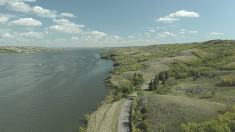 Drone-Over-Traveling-Car-On-Coastal-Road-At-Buffalo-Pound-Provincial-Park,-Saskatchewan,-Canada