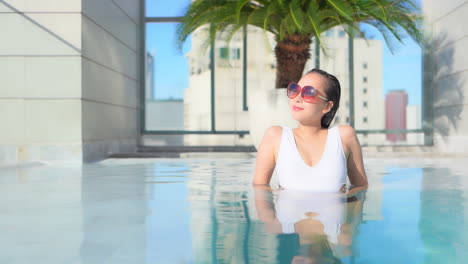 Mujer-Asiática-De-30-Años-Relajándose-En-La-Lujosa-Piscina-Al-Aire-Libre-En-La-Azotea-Del-Hotel-De-La-Ciudad-De-Bangkok