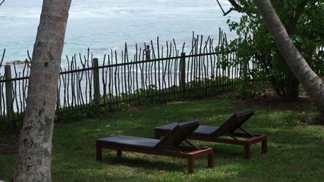 Two-Lounge-Chairs-Under-Palm-Trees-Facing-The-Ocean-At-Resort-In-Sri-Lanka