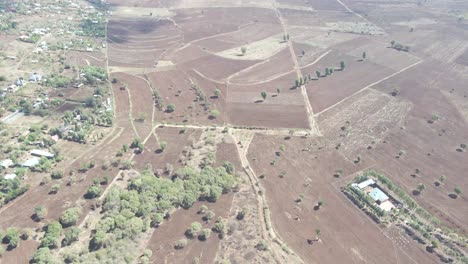 Vista-Aérea-De-Un-Campo-Vacío-Cerca-Del-Pueblo-En-Loitokitok,-Kenia