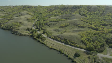 Aerial-view-as-car-drives-along-lake-in-Buffalo-Pound-Provincial-Park,-Canada