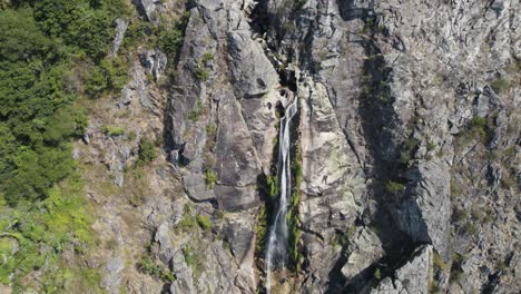 Water-stream-falling-from-rocky-cliff,-Frecha-da-Mizarela,-Portugal,-aerial-descend-view