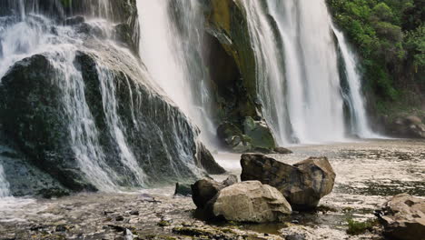 Pan-shot-of-powerful-Waihi-Falls-Waterfall-crashing-down-the-cliff-wall-during-sunny-day-in-New-Zealand