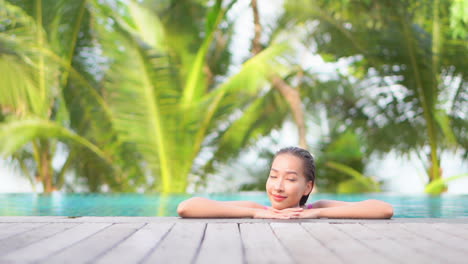 Asiatische-Frau-Genießt-Sonnigen-Tag-Im-Poolwasser-Des-Tropischen-Paradieses-Mit-Palmen-Im-Hintergrund