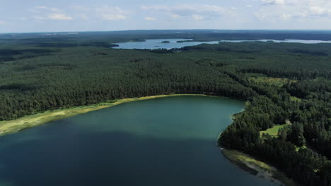 Lake-land-Lithuania-with-massive-forest-and-blue-waters,-high-angle-drone-view