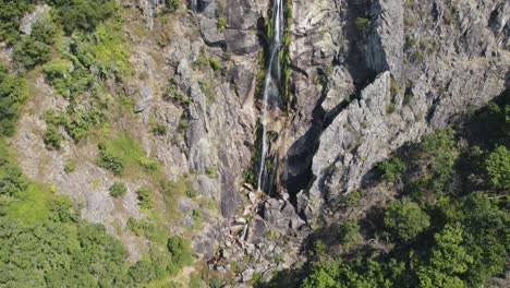Aerial-tilt-up-Majestic-Waterfall-on-stone-cliff,-Frecha-da-Mizarela---Portugal