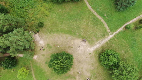 Green-and-vibrant-castle-mound-with-walkways,-top-down-aerial-view