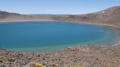 Pan-across-barren-blue-volcanic-lake-to-blonde-woman-taking-phone-pic
