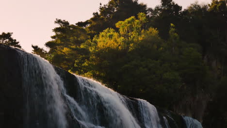 Fallender-Waihi-Wasserfall-Mit-Leuchtenden-Baumwipfeln-Bei-Sonnenuntergang-In-Neuseeland---Langsamer-Schwenk