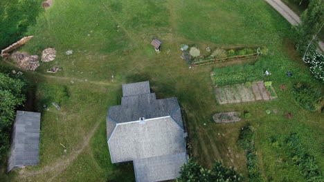 Old-countryside-homestead-with-green-grass-and-small-garden,-close-up-aerial-orbit-view