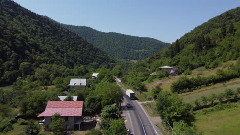 Drone-following-a-large-white-truck-through-a-valley-on-a-Georgian-road