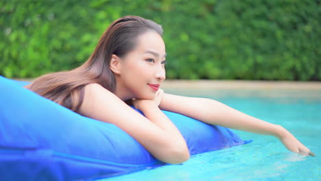 Attractive-young-Asian-woman-relaxing-on-blue-Inflatable-air-pool-mattress